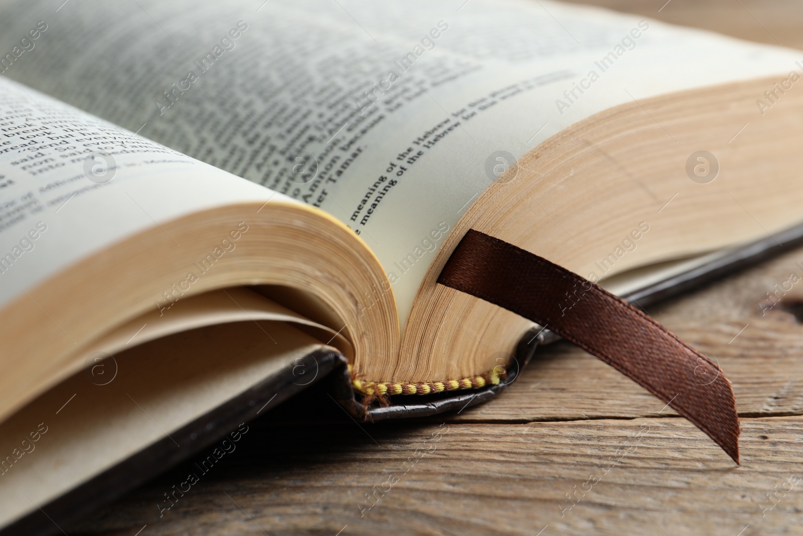 Photo of Open Bible on wooden table, closeup. Christian religious book