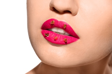 Beautiful young model with decorative spikes on lips against white background