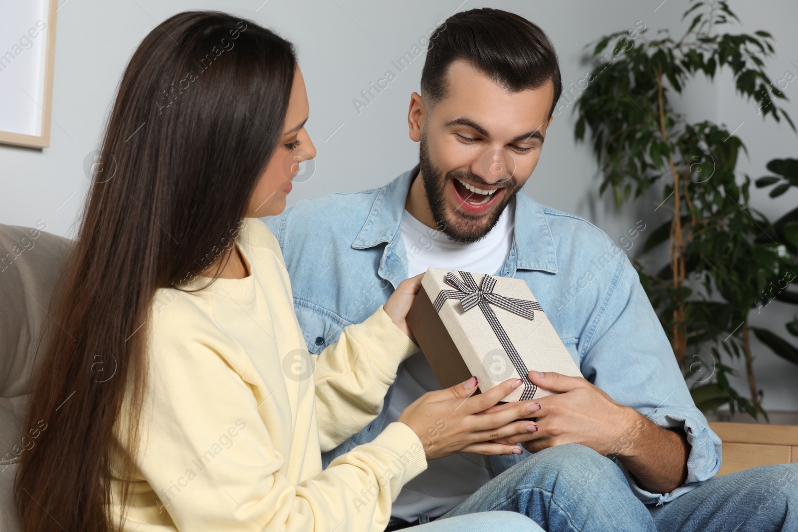 Photo of Woman presenting gift to her boyfriend at home