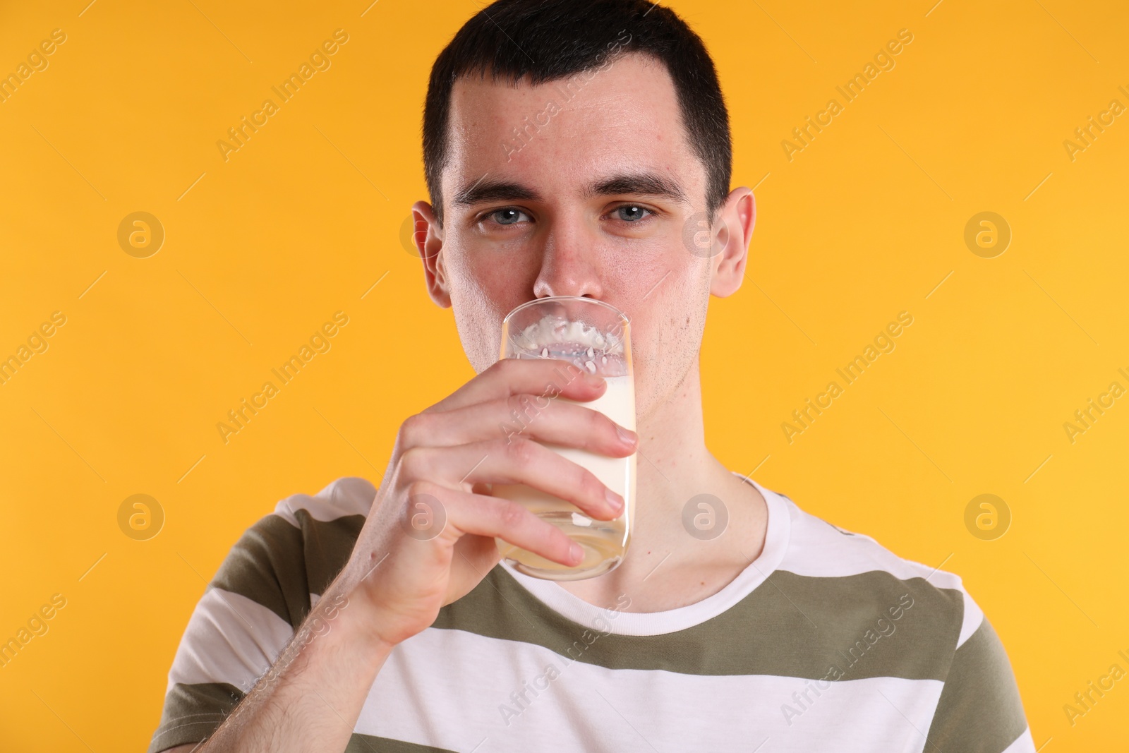 Photo of Milk mustache left after dairy product. Man drinking milk on orange background