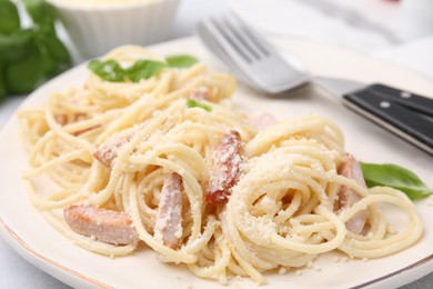 Photo of Tasty pasta Carbonara with basil leaves on plate, closeup