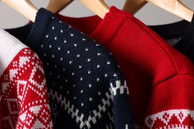 Different Christmas sweaters hanging on rack, closeup