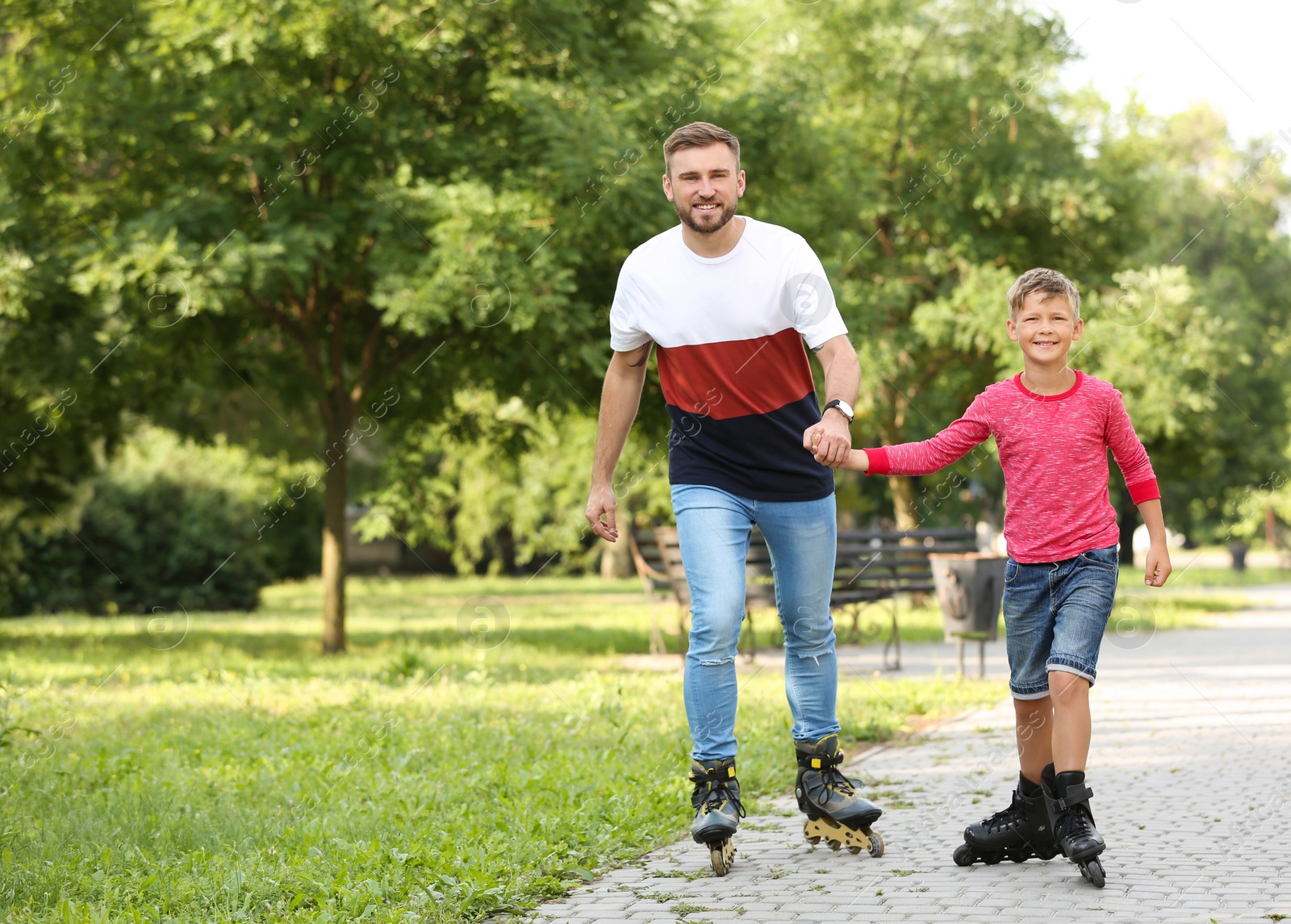 Photo of Father and son roller skating in summer park