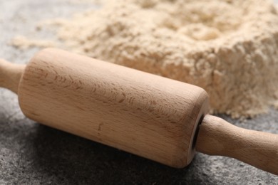 Rolling pin and scattered flour on grey textured table, closeup