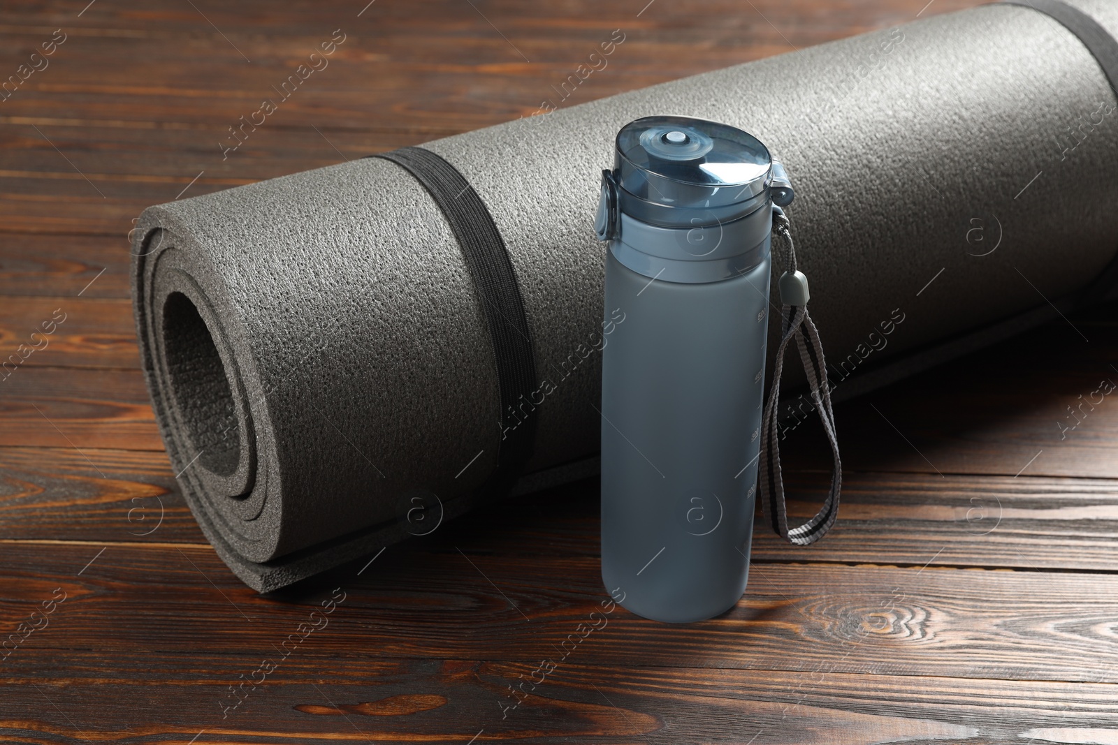 Photo of Yoga mat and bottle of water on wooden floor