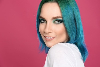 Young woman with bright dyed hair on pink background, closeup