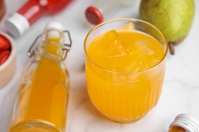 Photo of Tasty kombucha in glass and bottles on white table, closeup