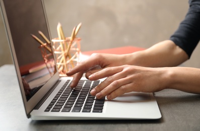 Woman using modern laptop at table, closeup