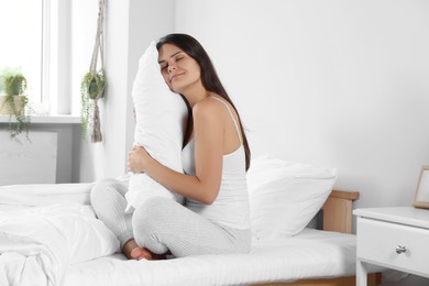 Photo of Beautiful young woman hugging pillow on bed at home