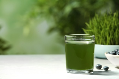 Photo of Glass of spirulina drink on table against blurred background, space for text