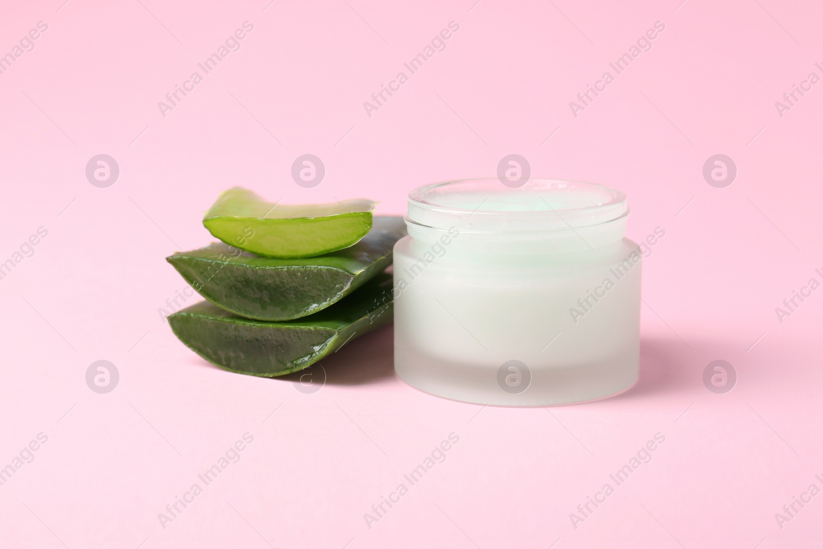 Photo of Jar of natural gel and cut aloe on pink background, closeup