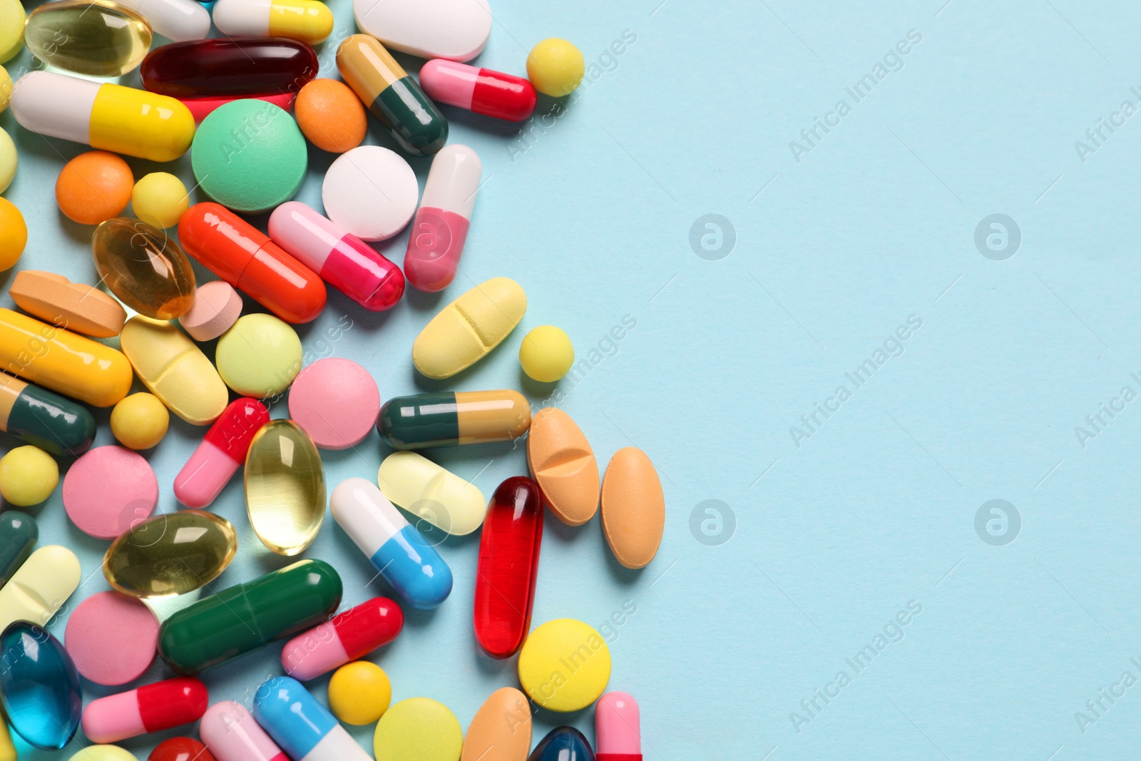 Photo of Many different pills on light blue background, flat lay. Space for text