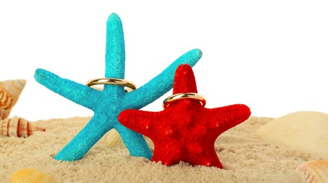 Photo of Honeymoon concept. Two golden rings, sea stars, seashells and sand isolated on white