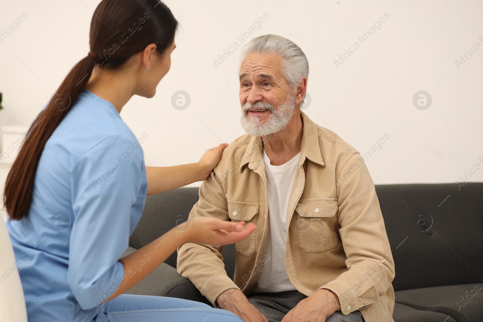 Photo of Health care and support. Nurse talking with elderly patient indoors