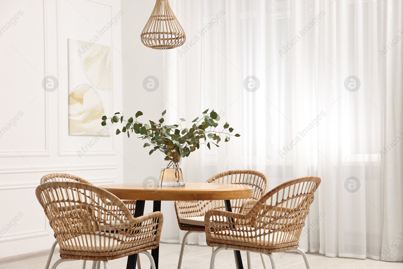 Photo of Dining room interior with comfortable furniture and eucalyptus branches