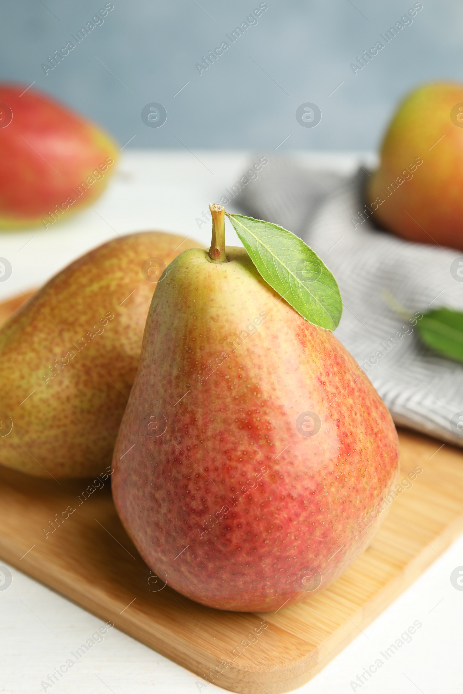 Photo of Ripe juicy pears on white wooden table against blue background