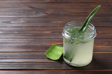 Photo of Fresh aloe juice in jar and leaves on wooden table, space for text