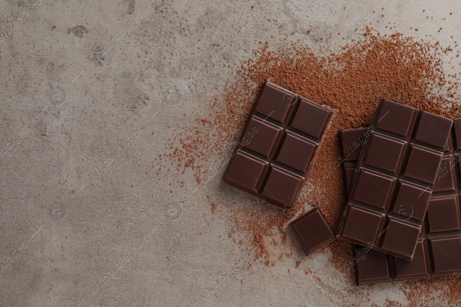 Photo of Delicious dark chocolate and cocoa powder on light grey table, flat lay. Space for text