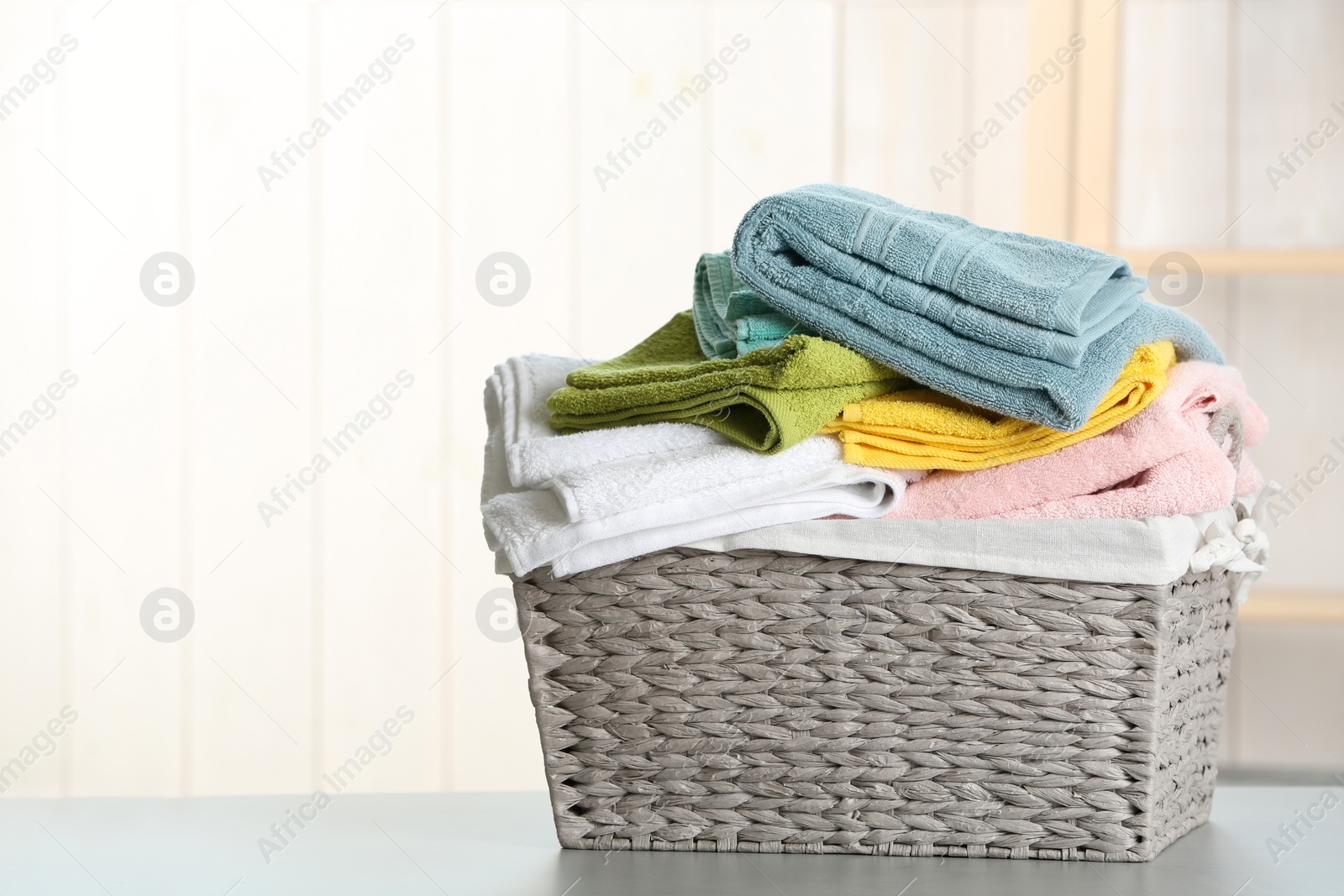 Photo of Basket with clean laundry on table at home, space for text