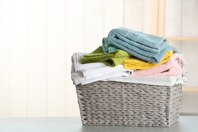 Basket with clean laundry on table at home, space for text