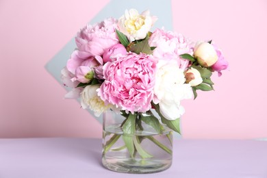 Photo of Bouquet of beautiful peonies in vase on lilac table