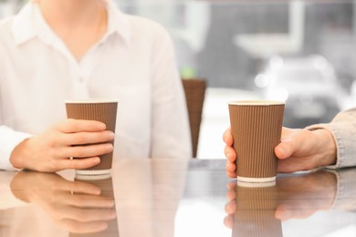 Photo of Women holding takeaway paper cups at table, closeup. Coffee to go