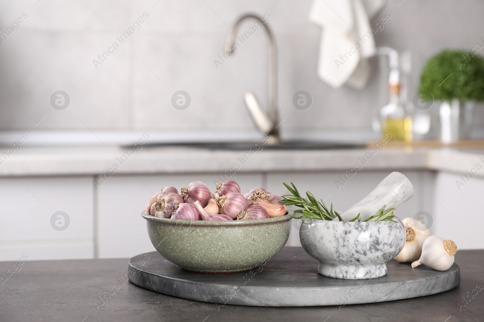 Photo of Fresh raw garlic and rosemary on grey table, space for text