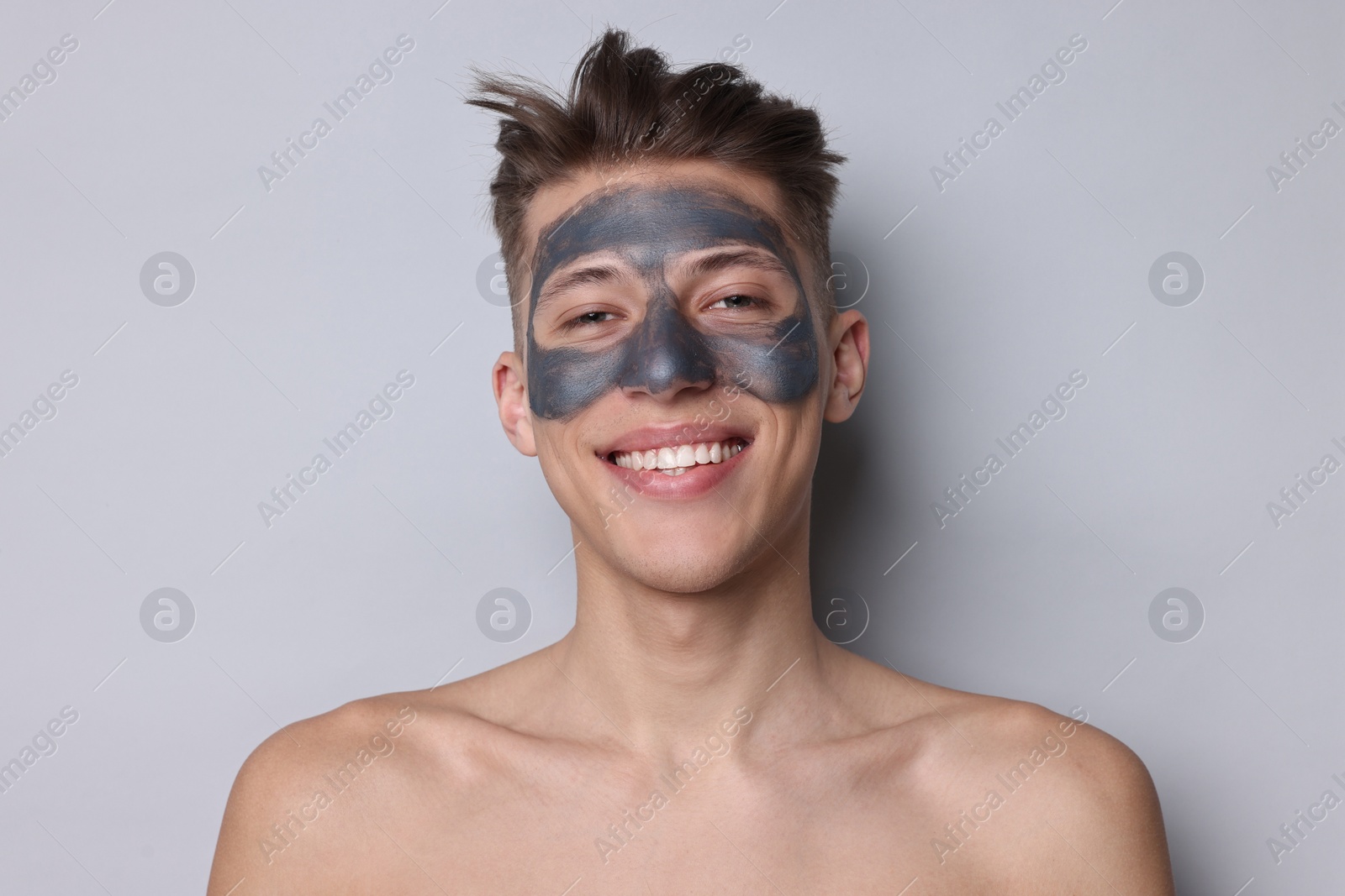 Photo of Handsome man with clay mask on his face against light grey background