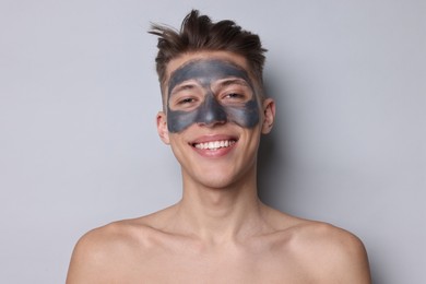 Photo of Handsome man with clay mask on his face against light grey background