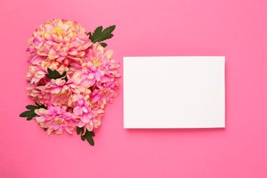 Photo of Beautiful chrysanthemums and blank card on pink background, flat lay. Space for text