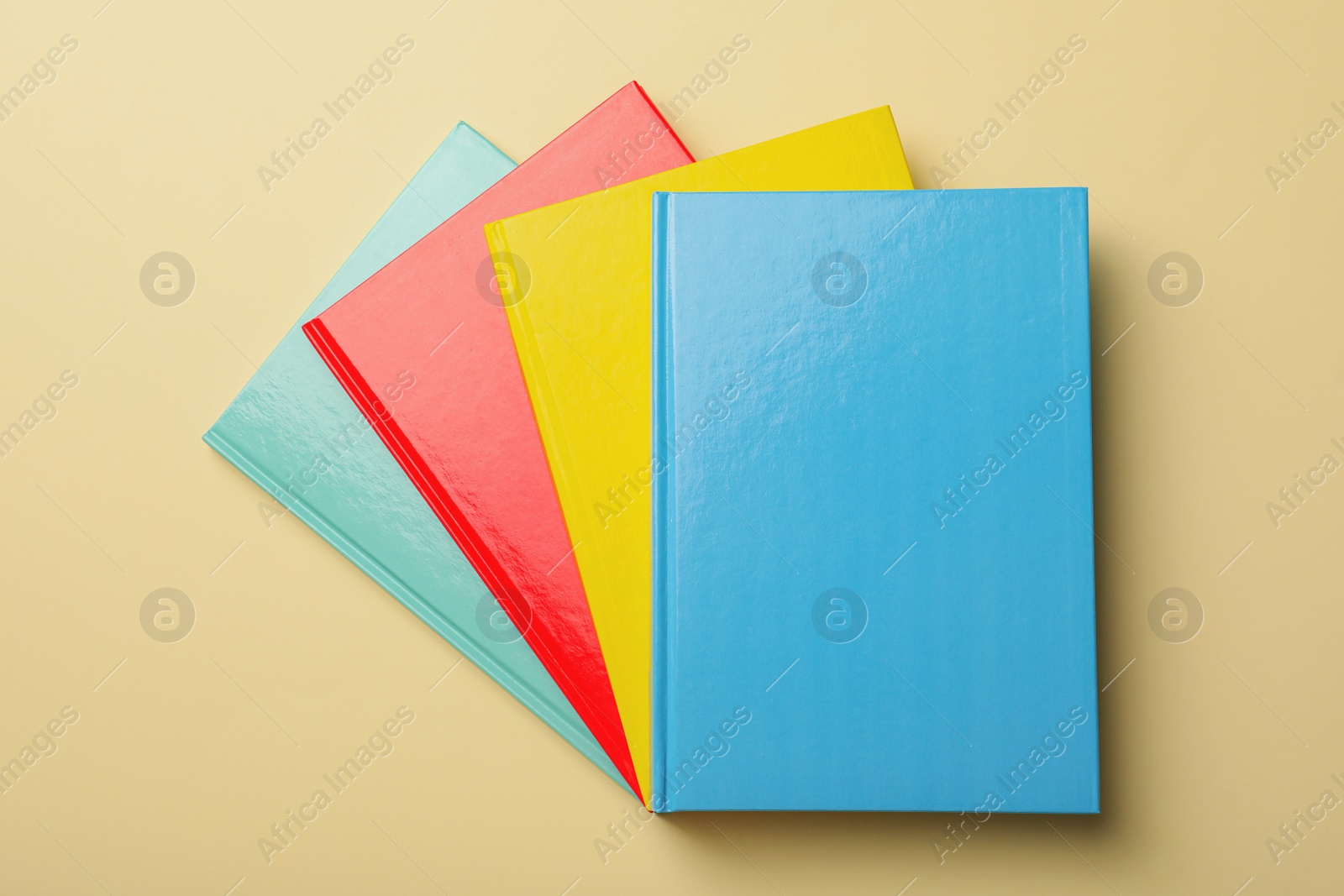 Photo of New colorful planners on beige background, top view