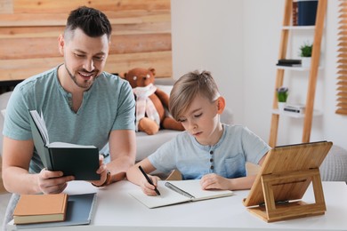 Boy with father doing homework at table indoors