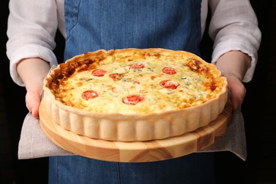 Photo of Woman with delicious homemade cheese quiche on black background, closeup