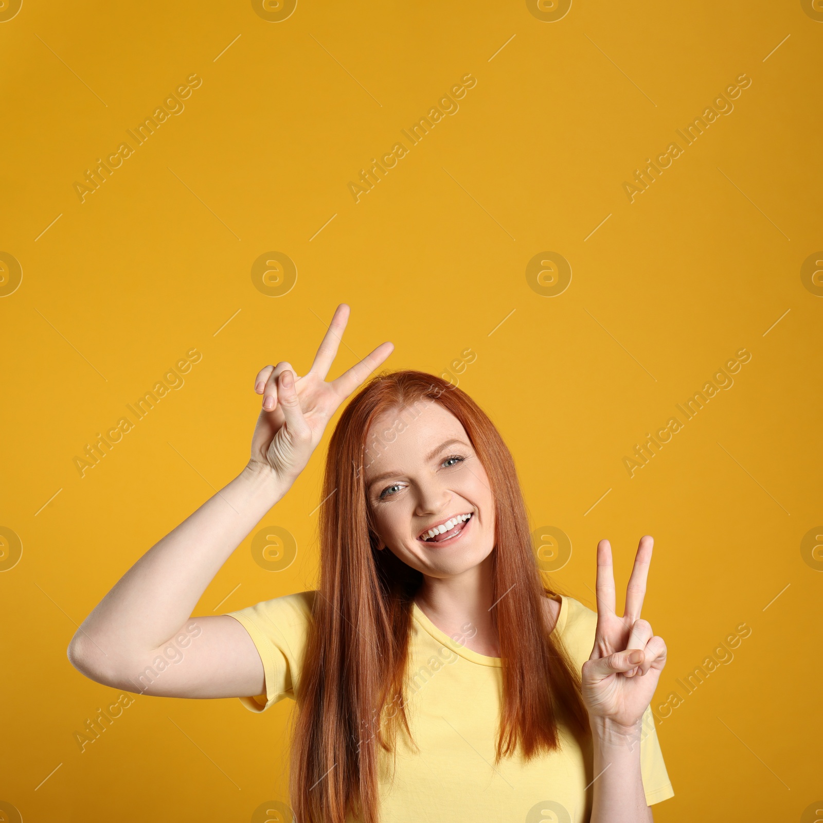 Photo of Portrait of cheerful young woman with gorgeous red hair posing on yellow background