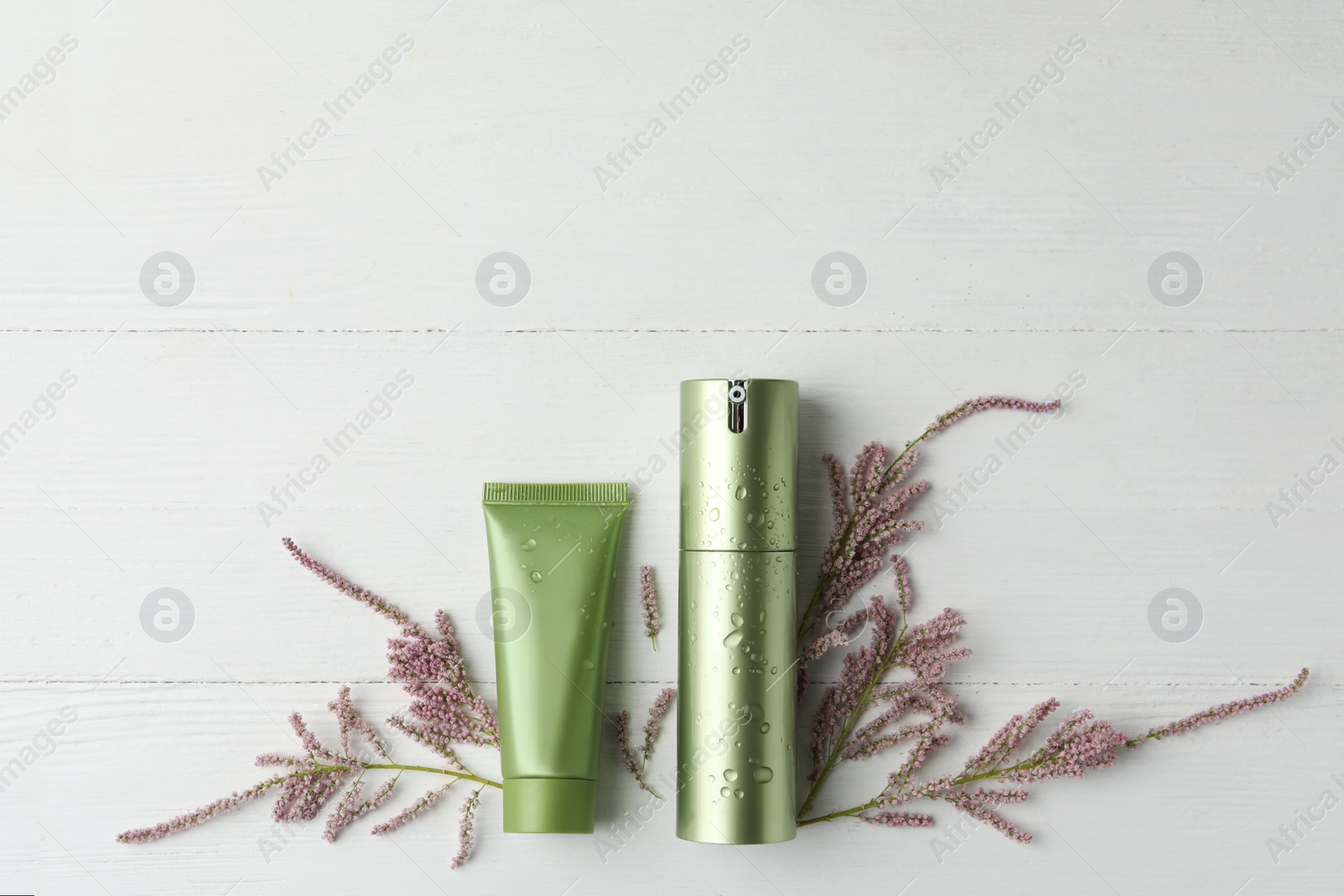 Photo of Cosmetic products and flowers on white wooden table, flat lay. Space for text