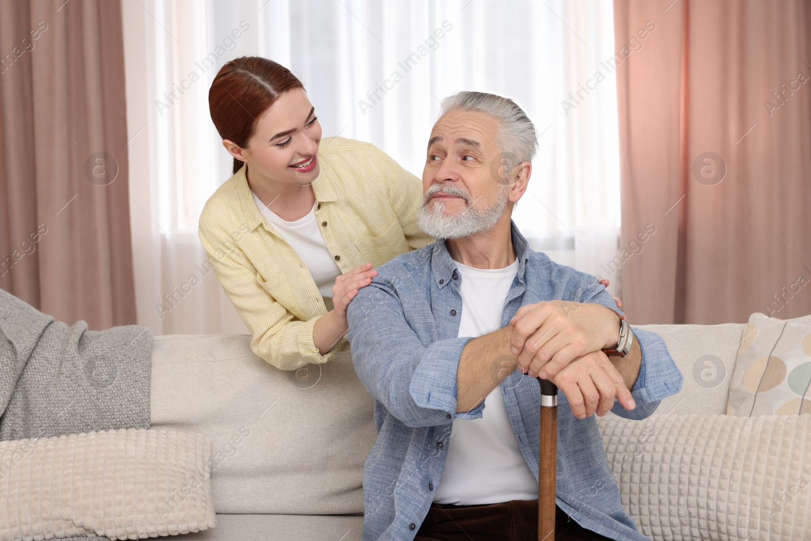 Photo of Caregiver and senior man with walking cane at home