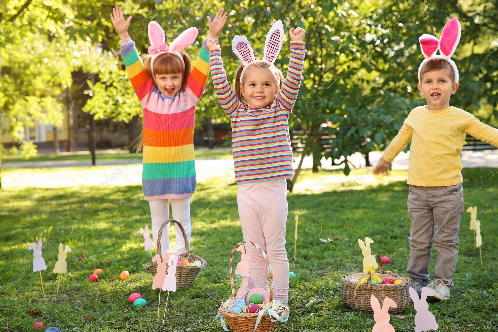 Photo of Cute little children hunting eggs in park. Easter tradition