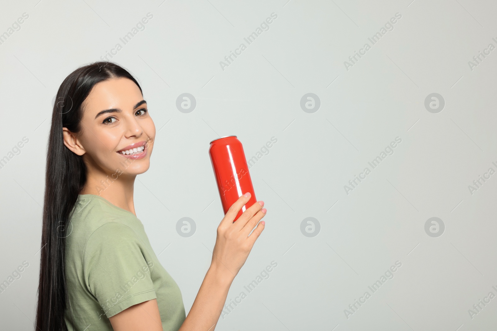 Photo of Beautiful happy woman holding red beverage can on light grey background. Space for text