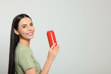 Photo of Beautiful happy woman holding red beverage can on light grey background. Space for text