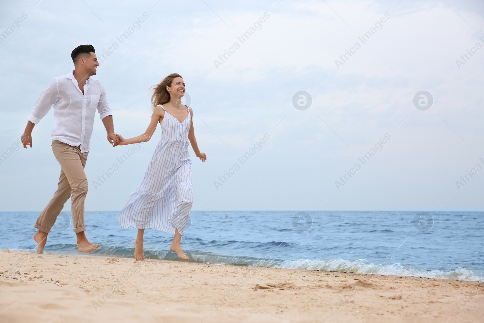 Photo of Happy couple having romantic walk on beach. Space for text