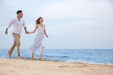 Photo of Happy couple having romantic walk on beach. Space for text