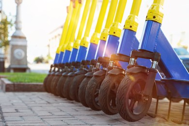 Photo of Many modern electric scooters parked on city street, closeup. Rental service