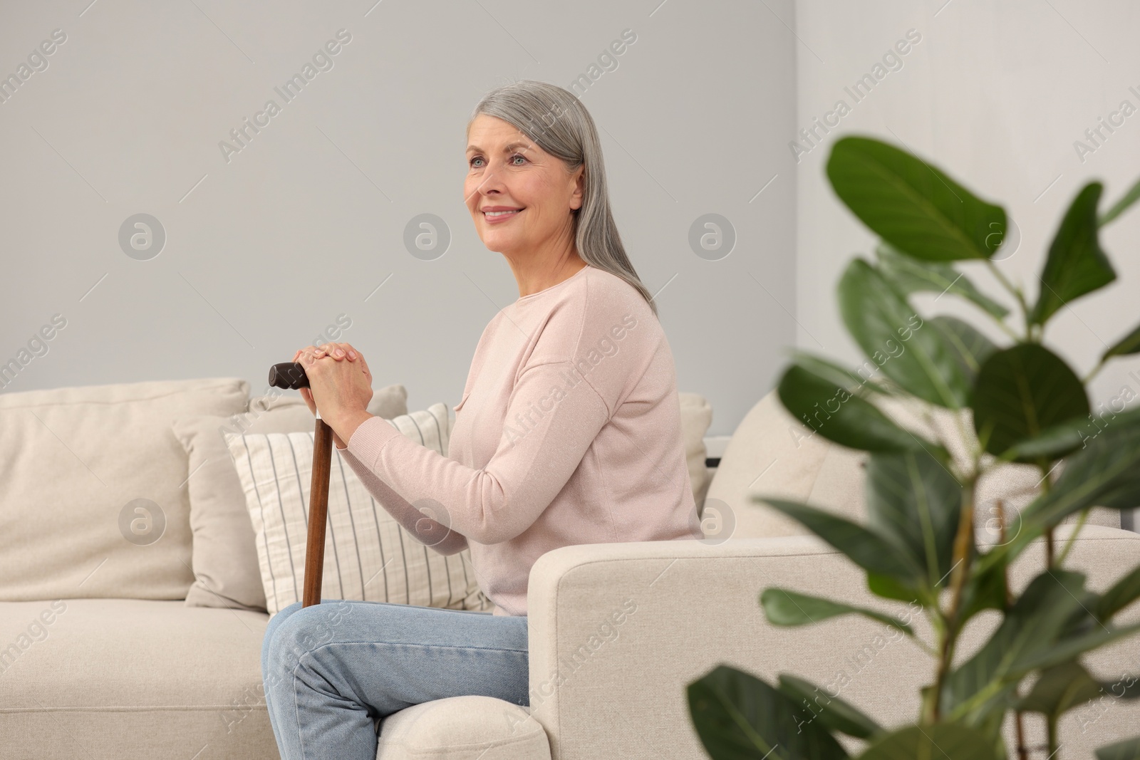 Photo of Mature woman with walking cane on sofa indoors