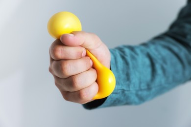 Photo of Man squeezing antistress ball on grey background, closeup