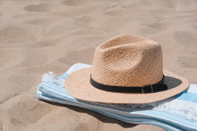 Photo of Straw hat and beach towel on sand