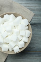 Photo of White sugar cubes in bowl on wooden table, top view