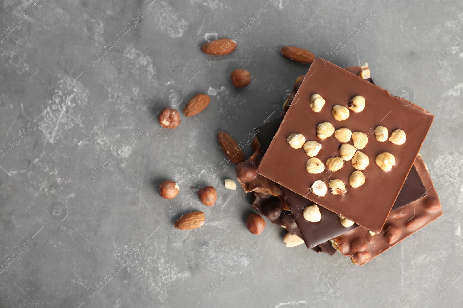 Photo of Delicious milk and dark chocolate bars with nuts on table, top view