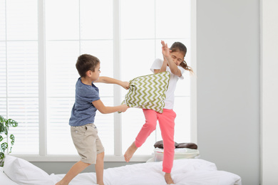 Happy children having pillow fight in bedroom