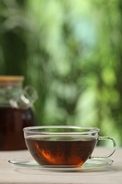 Photo of Cup of aromatic tea on white table outdoors. Space for text