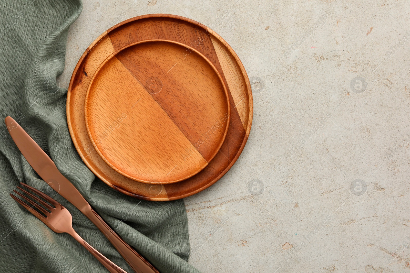 Photo of Stylish setting with cutlery, napkin and plates on light table, top view. Space for text